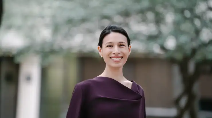 Professional traditional headshot of a woman in a maroon dress, standing outside with a soft-focus background—ideal for LinkedIn profiles, company directories, and corporate uses.